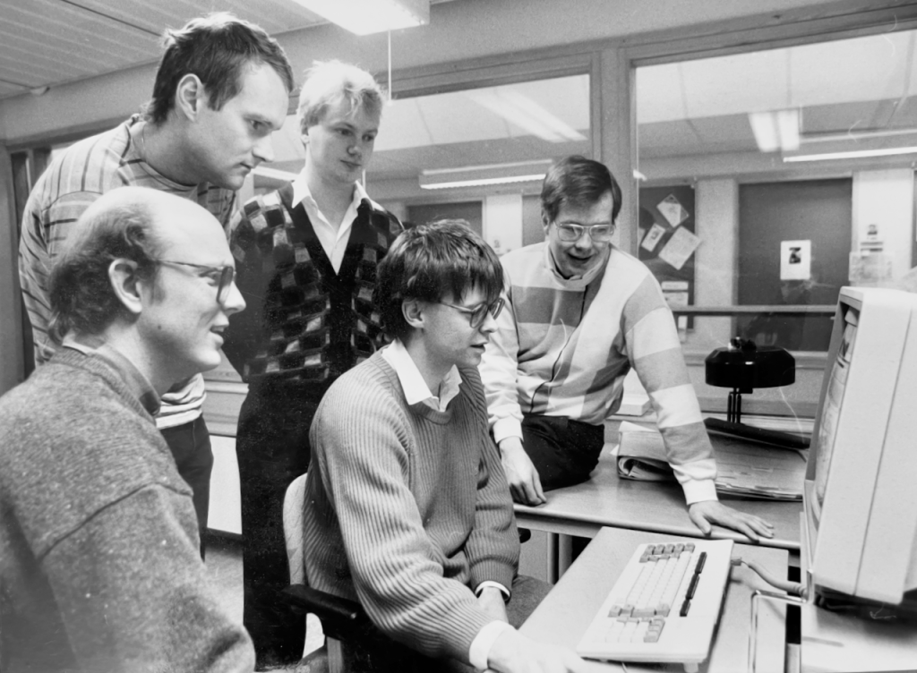 Black-and-white photo of five researchers at Linköping University in 1986, gathered around a Xerox Lisp machine. From left to right: Nils Dahlbäck, Arne Jönsson, Magnus Merkel, Mats Wirén, and Lars Ahrenberg. The group was part of the newly founded Natural Language Processing Laboratory (NLPLAB), a hub for early research in human-computer interaction and computational linguistics.